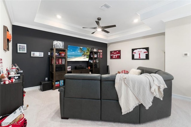 cinema featuring ceiling fan, ornamental molding, a raised ceiling, and light carpet