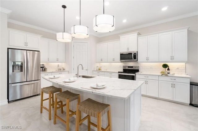 kitchen featuring pendant lighting, sink, appliances with stainless steel finishes, white cabinetry, and a kitchen island with sink