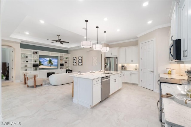 kitchen with appliances with stainless steel finishes, pendant lighting, white cabinetry, sink, and a center island with sink