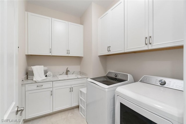 clothes washing area featuring separate washer and dryer, sink, and cabinets