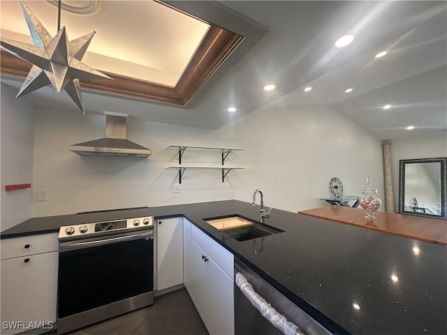 kitchen featuring sink, white cabinetry, dark tile patterned floors, oven, and wall chimney range hood