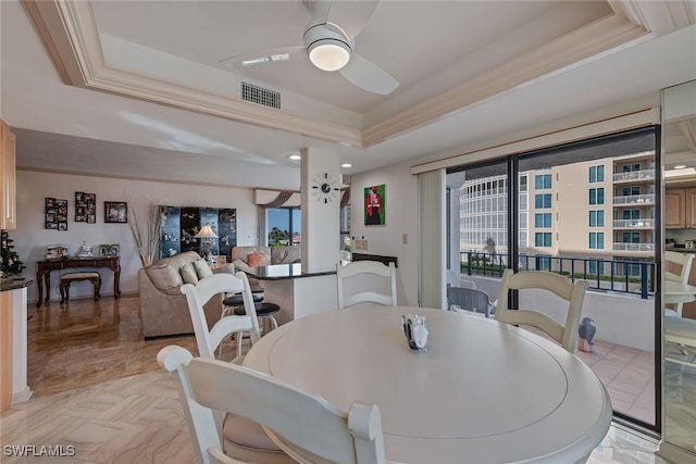 dining room featuring crown molding, a raised ceiling, and ceiling fan