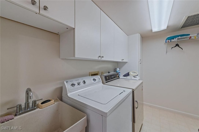 laundry area with cabinets, washing machine and dryer, and sink