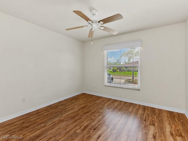 empty room featuring ceiling fan, baseboards, and wood finished floors