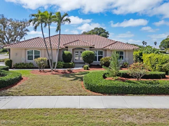 mediterranean / spanish-style house featuring stucco siding, a tile roof, and a front yard