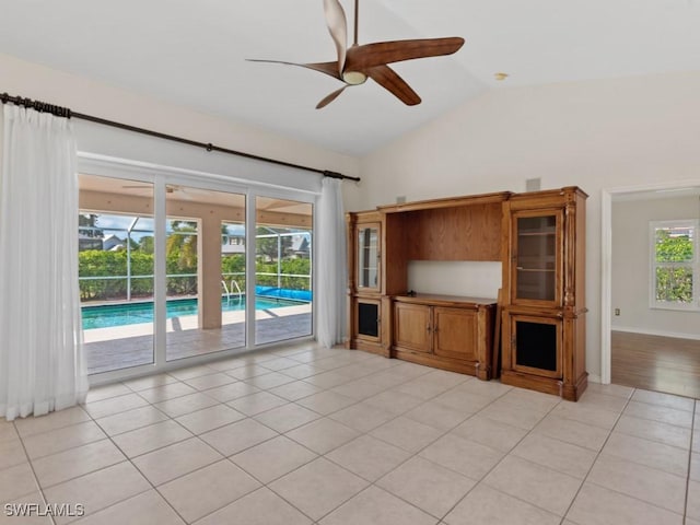 unfurnished living room with a ceiling fan, vaulted ceiling, baseboards, and light tile patterned floors