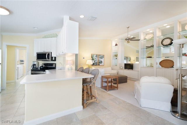 kitchen with appliances with stainless steel finishes, a breakfast bar, white cabinetry, ceiling fan, and kitchen peninsula