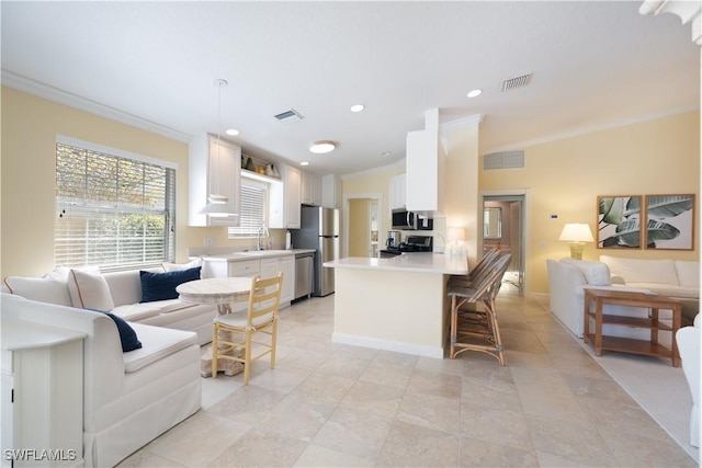 kitchen featuring appliances with stainless steel finishes, decorative light fixtures, sink, white cabinets, and crown molding