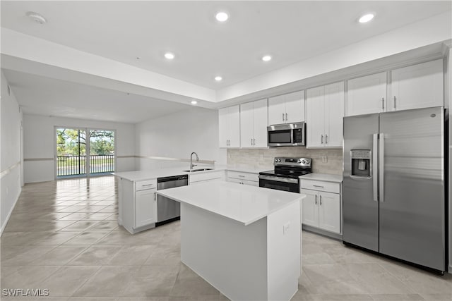 kitchen featuring appliances with stainless steel finishes, sink, white cabinets, a center island, and kitchen peninsula