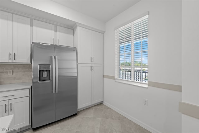 kitchen featuring white cabinetry, light tile patterned flooring, stainless steel fridge with ice dispenser, and tasteful backsplash