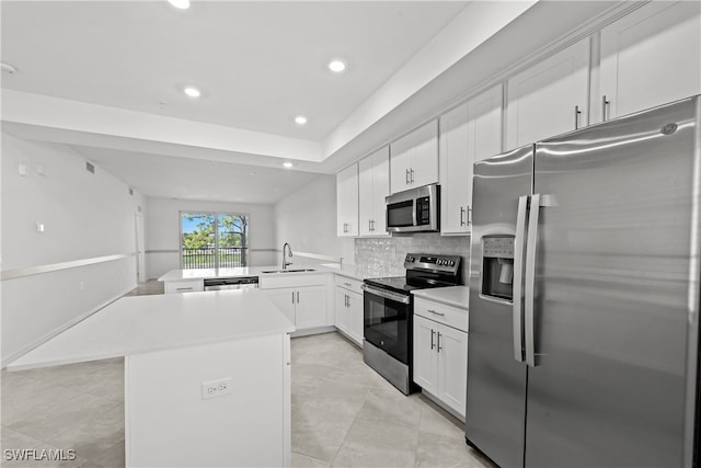 kitchen featuring sink, stainless steel appliances, white cabinets, a kitchen island, and kitchen peninsula