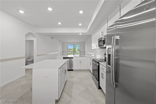 kitchen with a kitchen island, appliances with stainless steel finishes, sink, white cabinets, and kitchen peninsula