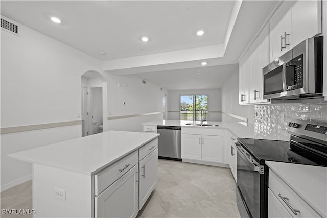 kitchen featuring sink, white cabinetry, appliances with stainless steel finishes, a kitchen island, and backsplash