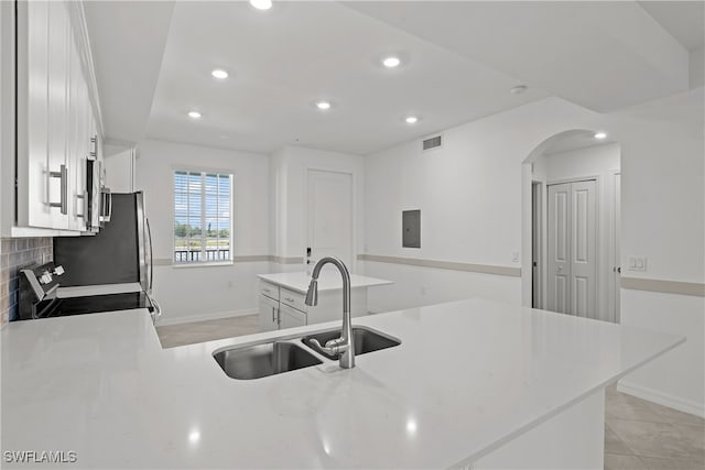 kitchen featuring sink, white cabinets, stove, light tile patterned floors, and kitchen peninsula