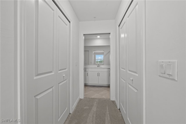 corridor featuring sink and light colored carpet