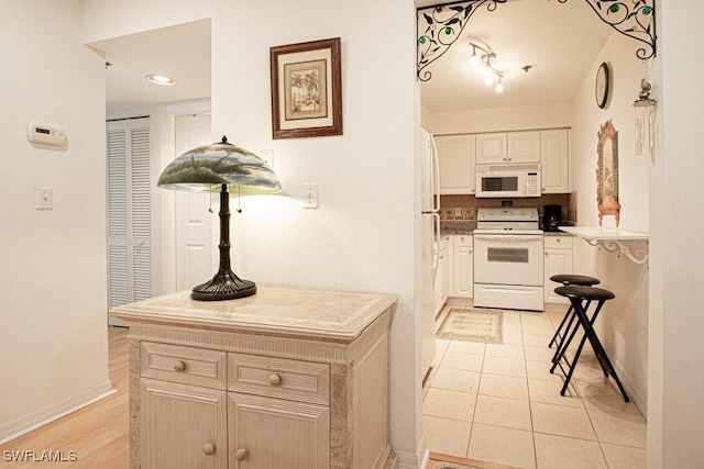 kitchen with tasteful backsplash, light tile patterned flooring, and white appliances