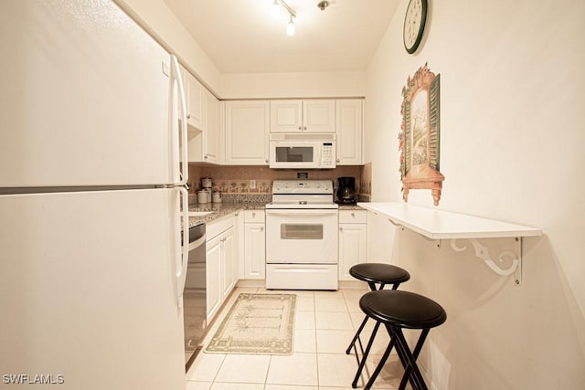 kitchen with a breakfast bar area, white cabinets, light tile patterned floors, kitchen peninsula, and white appliances