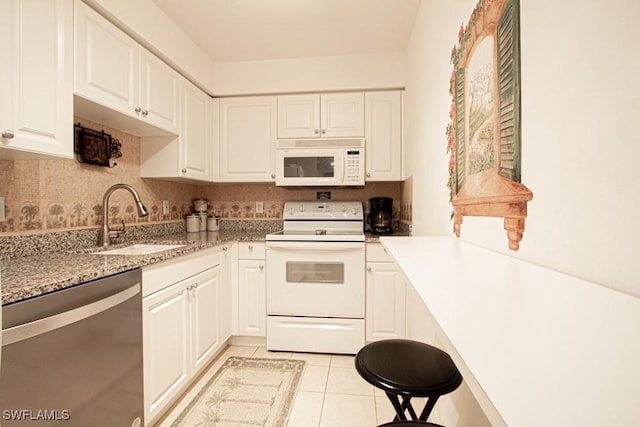 kitchen with light tile patterned flooring, sink, white cabinets, white appliances, and backsplash