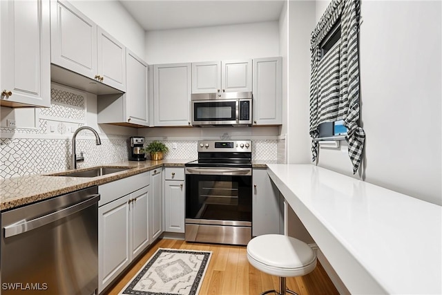 800 S Golf Dr Unit N205, Naples, FL 34102 - kitchen with light stone counters, a sink, decorative backsplash, light wood-style floors, and appliances with stainless steel finishes