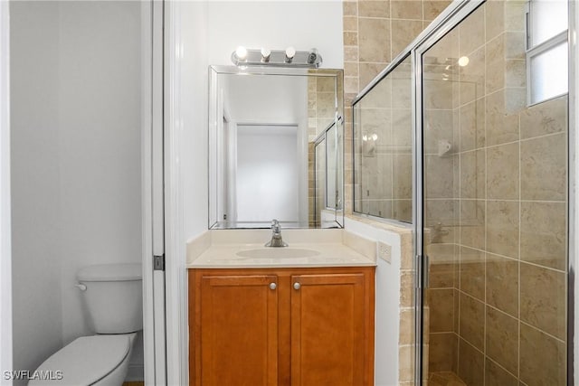 bathroom featuring vanity, a shower with door, and toilet