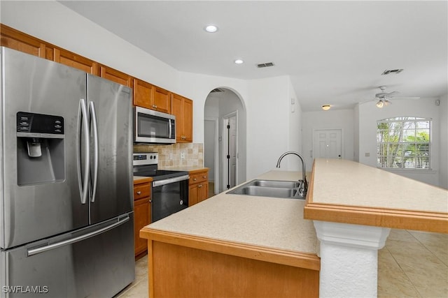 kitchen featuring sink, appliances with stainless steel finishes, an island with sink, light tile patterned flooring, and decorative backsplash