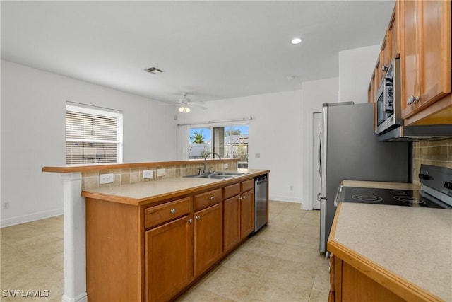 kitchen with sink, appliances with stainless steel finishes, an island with sink, ceiling fan, and backsplash