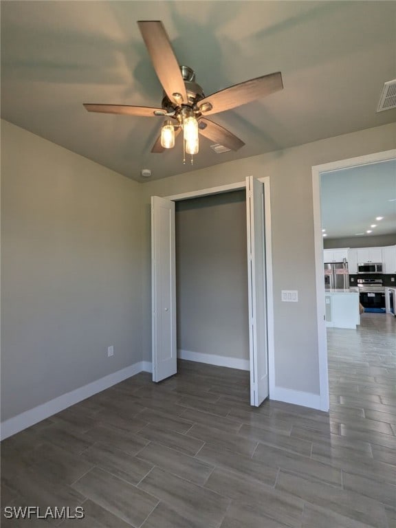 unfurnished bedroom featuring wood finish floors, visible vents, stainless steel refrigerator with ice dispenser, and baseboards