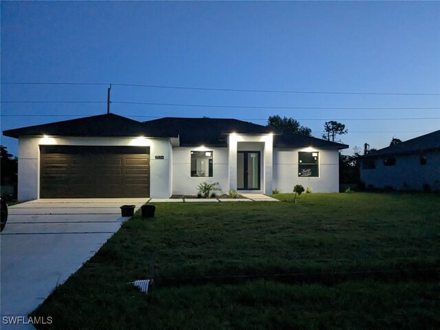 view of front facade with stucco siding, an attached garage, concrete driveway, and a front lawn