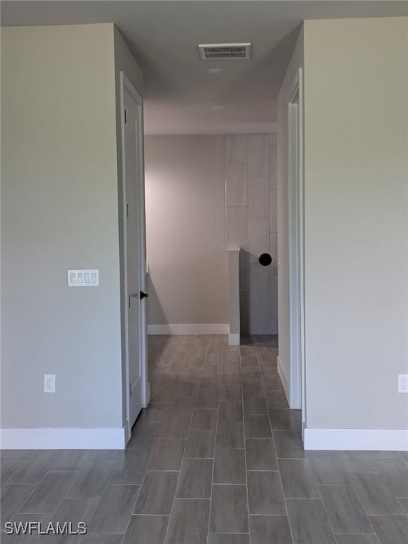 hallway featuring baseboards and visible vents