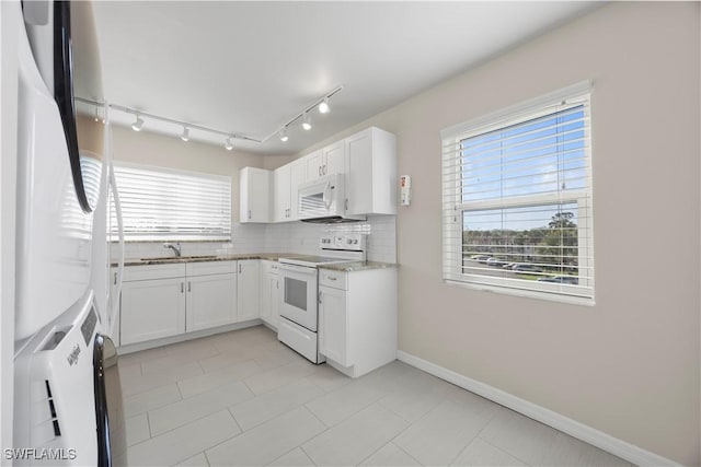4372 27th Ct SW Unit 301, Naples, FL 34116 - kitchen with white appliances, a sink, backsplash, white cabinets, and baseboards