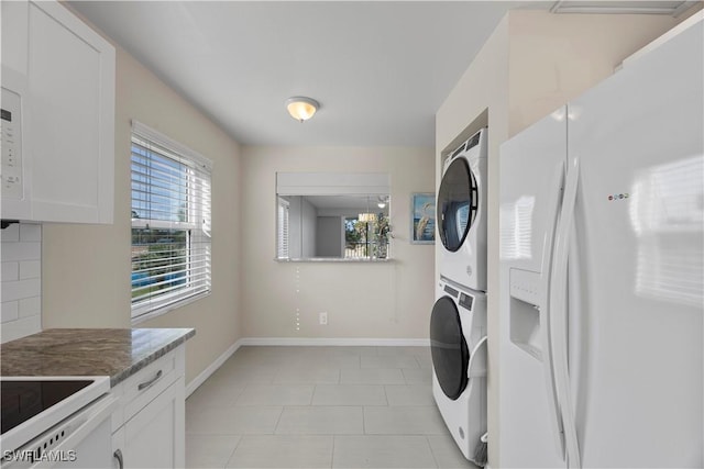 4372 27th Ct SW Unit 301, Naples, FL 34116 - laundry room featuring stacked washing machine and dryer, baseboards, and light tile patterned floors
