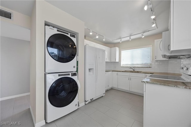 4372 27th Ct SW Unit 301, Naples, FL 34116 - washroom with stacked washing machine and dryer, track lighting, baseboards, and light tile patterned floors