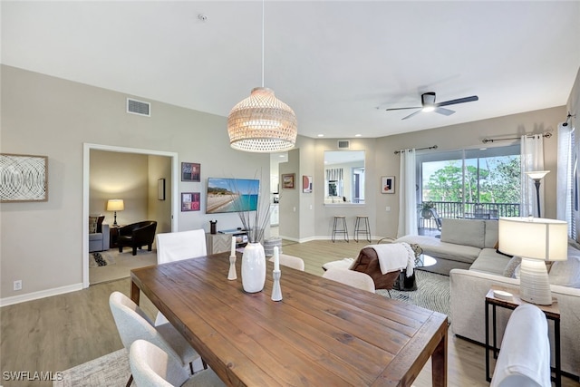 dining area with ceiling fan with notable chandelier and light hardwood / wood-style flooring