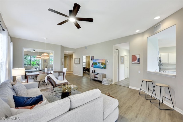 living room with ceiling fan and light wood-type flooring