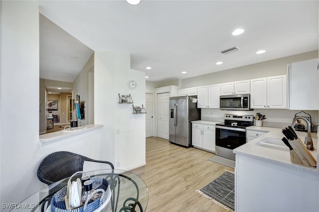 kitchen featuring stainless steel appliances, sink, light hardwood / wood-style floors, and white cabinets