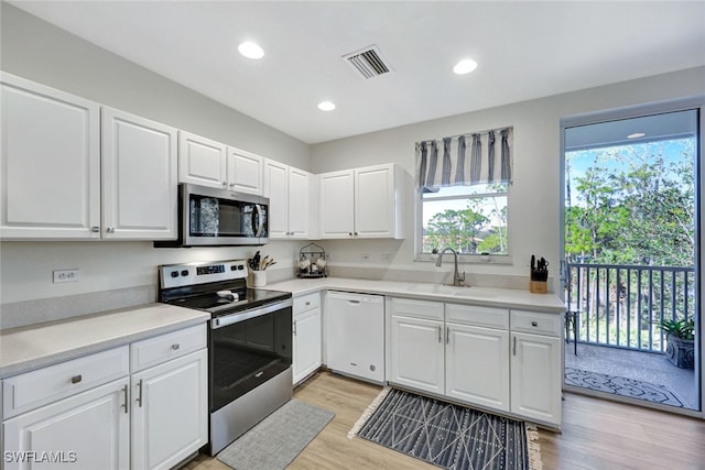 kitchen featuring white cabinetry, sink, stainless steel appliances, and light hardwood / wood-style floors