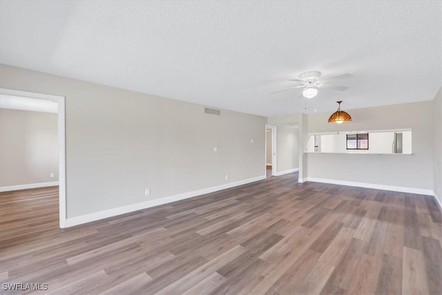 unfurnished living room featuring ceiling fan, light hardwood / wood-style flooring, and a textured ceiling