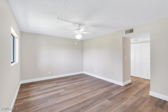 unfurnished room with ceiling fan, hardwood / wood-style flooring, and a textured ceiling