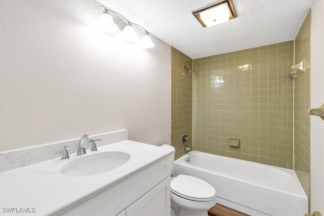 full bathroom featuring tiled shower / bath, vanity, a textured ceiling, and toilet