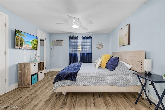 bedroom featuring ceiling fan, a wall mounted AC, and light hardwood / wood-style flooring