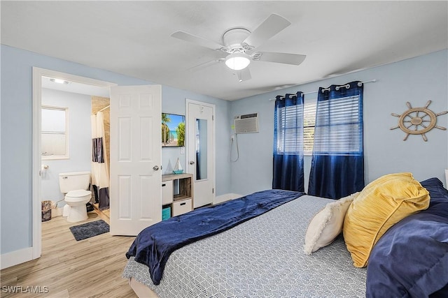 bedroom with ceiling fan, connected bathroom, a wall mounted AC, and light hardwood / wood-style flooring