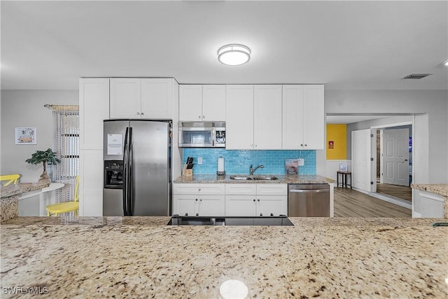 kitchen featuring sink, stainless steel appliances, light stone countertops, decorative backsplash, and white cabinets