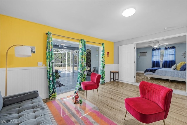 living room with hardwood / wood-style flooring, a wall mounted AC, and ceiling fan