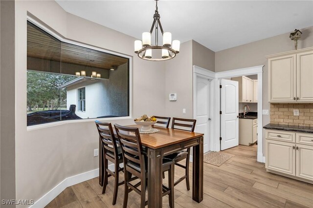 dining area with a chandelier, sink, and light wood-type flooring