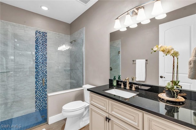 bathroom with vanity, hardwood / wood-style floors, toilet, and tiled shower