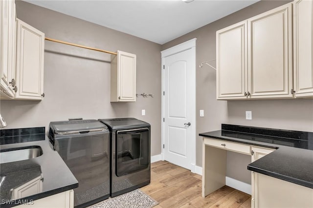 laundry area with separate washer and dryer, sink, light hardwood / wood-style floors, and cabinets