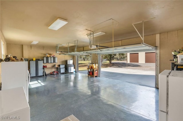 garage featuring a garage door opener, washing machine and dryer, water heater, and white refrigerator