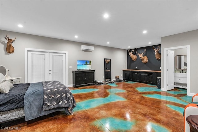 bedroom with concrete flooring, connected bathroom, a wall mounted AC, and a closet