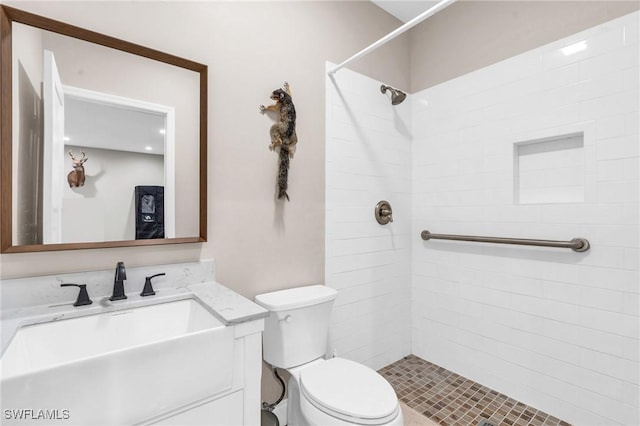 bathroom featuring vanity, toilet, and a tile shower