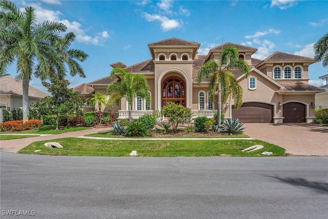 mediterranean / spanish-style home with a garage and a front lawn